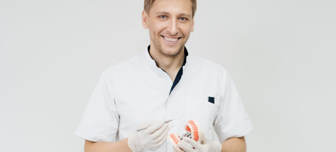 Dentist pointing to a plaster cast on white background. Explaining about teeth care